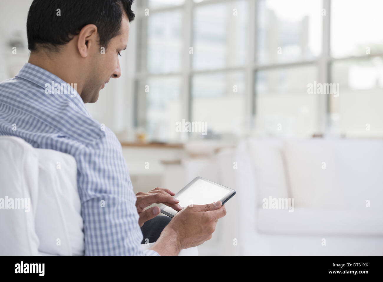 Professionisti in ufficio una luminosa e ariosa e luogo di lavoro di un uomo seduto utilizzando una tavoletta digitale Foto Stock