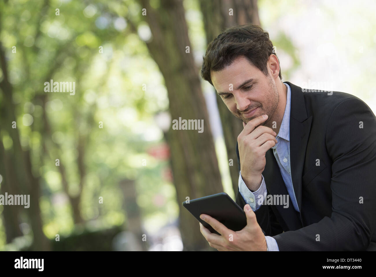 Un uomo seduto in un parco con la sua tavoletta digitale Foto Stock