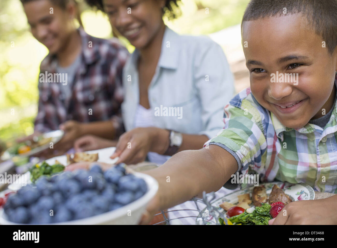 Un picnic in famiglia in un ombroso bosco di adulti e bambini seduti a un tavolo Foto Stock