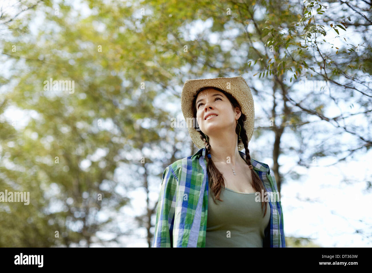 Una ragazza in un cappello di paglia a piedi nei boschi Foto Stock