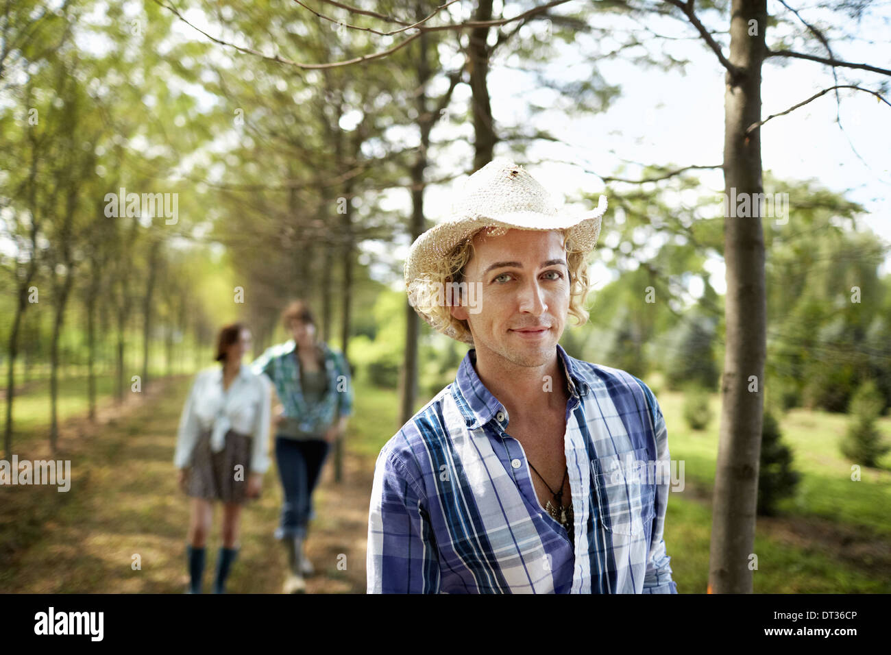 Un gruppo di amici a piedi verso il basso di un viale di alberi nel bosco Foto Stock