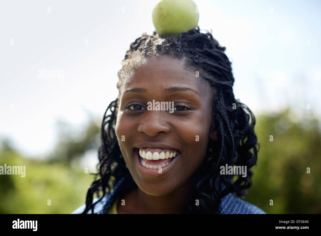 Una giovane donna con una mela verde sulla cima della sua testa Foto Stock