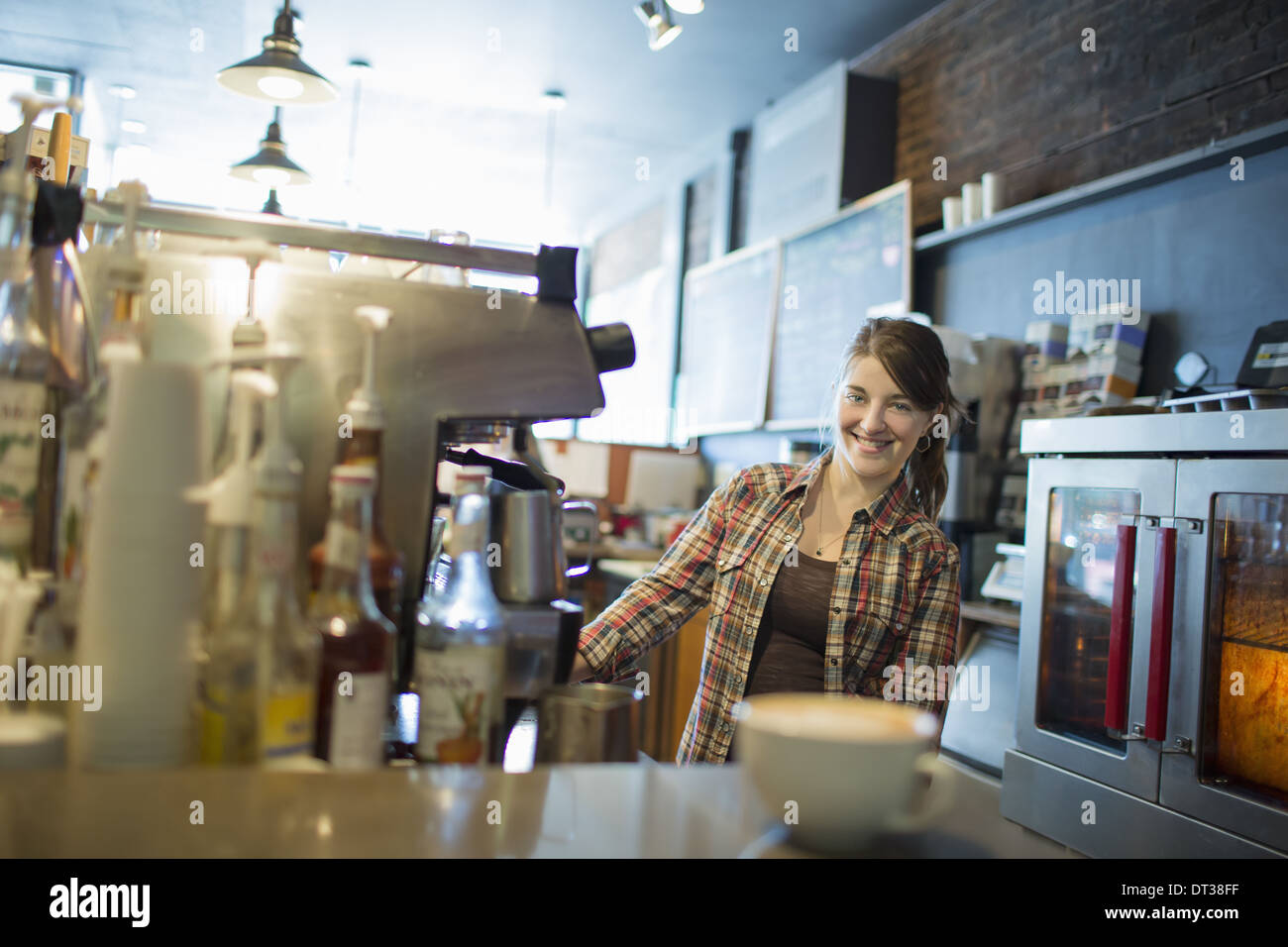 Una persona, il barista, dietro il contatore in una caffetteria. Una macchina per caffè cappuccino sul contatore. Foto Stock