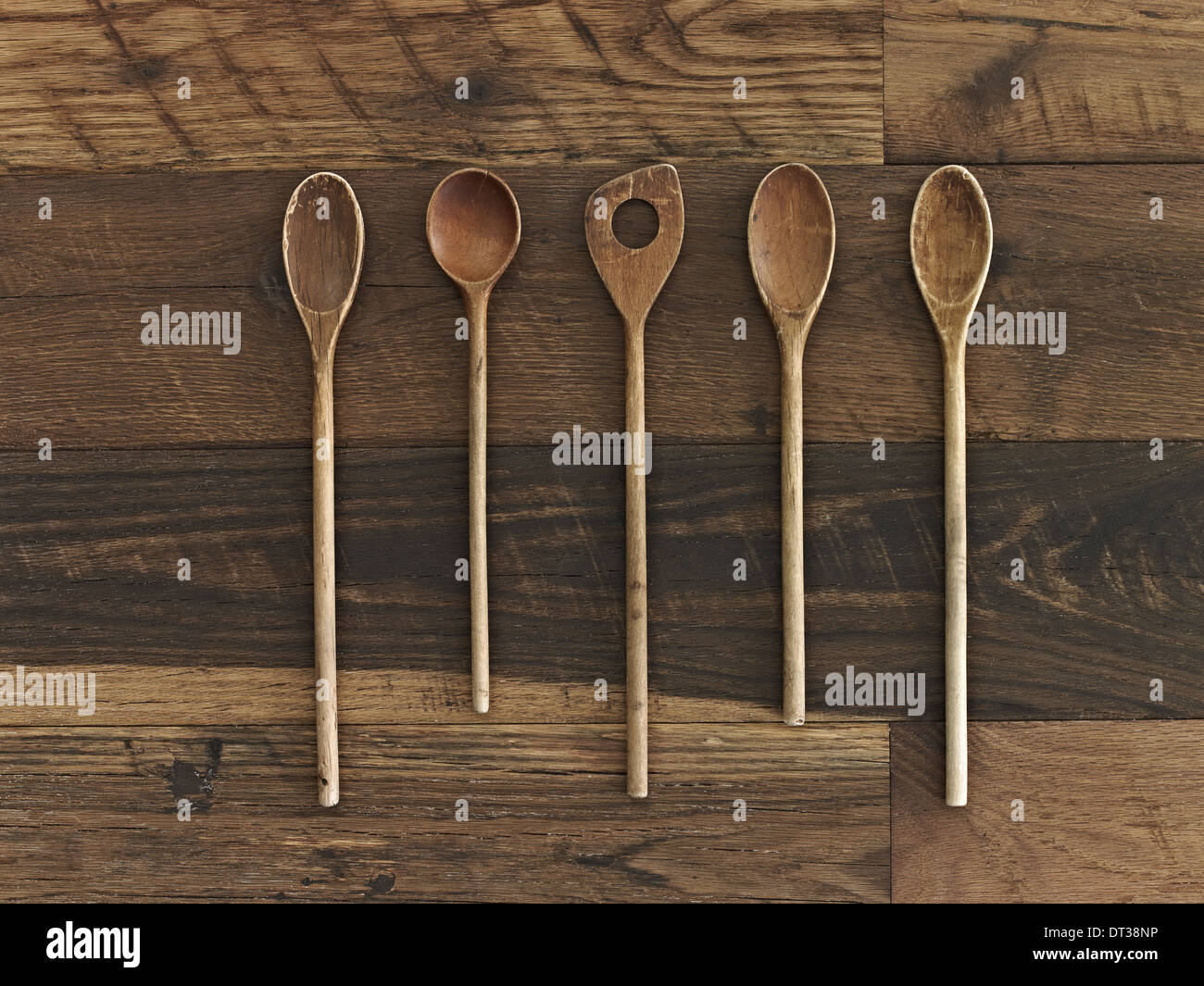 Cucina casalinga. Un tavolo di legno con una variegata a grana di legno e colore. Cinque cucchiai di legno in una fila. Foto Stock Cucina casalinga. Un tavolo di legno con una variegata a grana di legno e colore. Cinque cucchiai di legno in una fila. Foto Stock