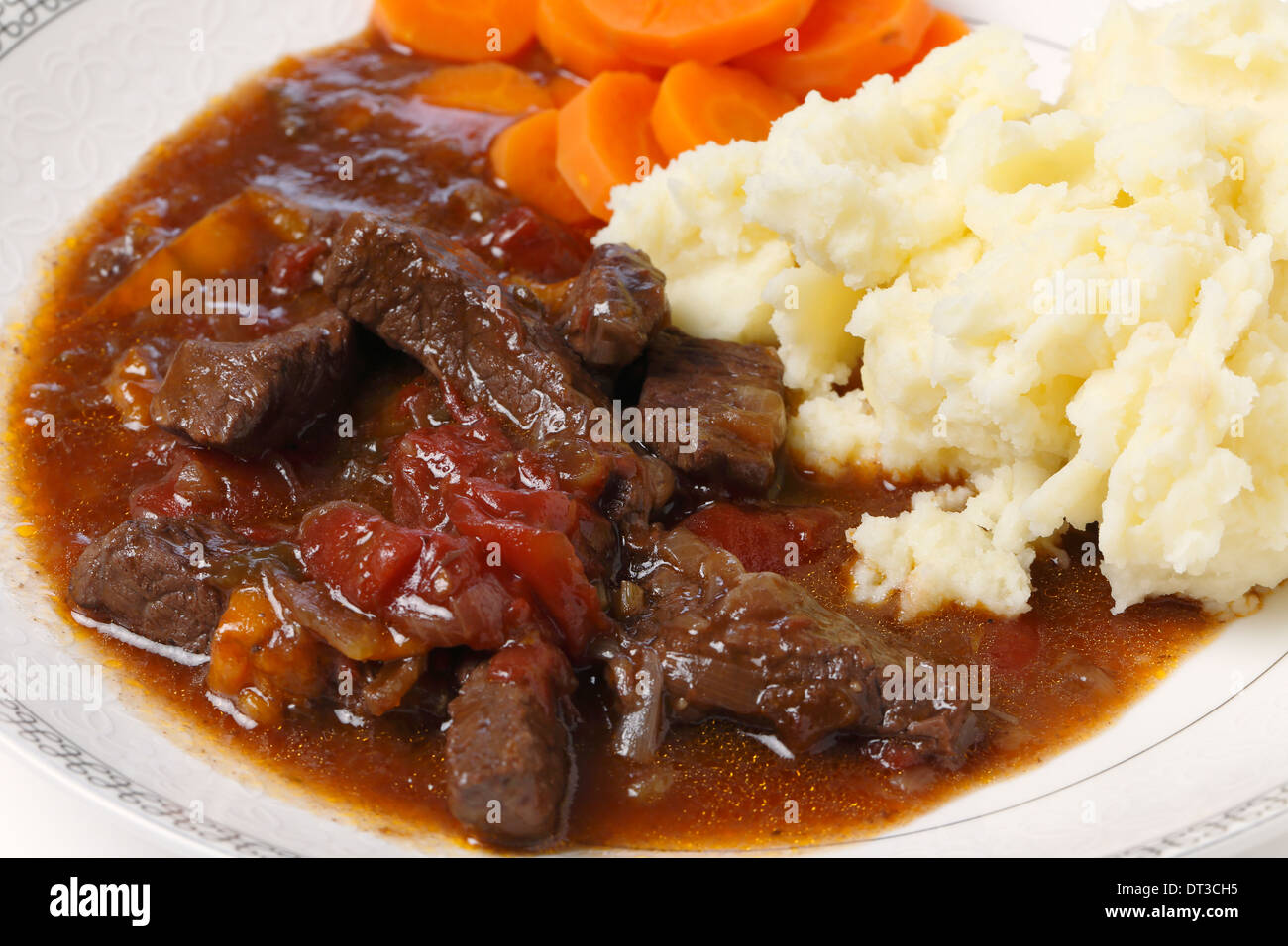 La carne bovina britannica e pomodoro casseruola, servita con purè di patate e carote bollite, primo piano Foto Stock