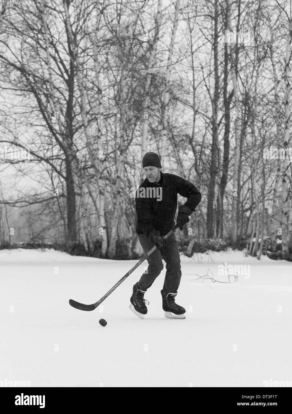 WARREN, Vermont, USA - Uomo pattinaggio sul laghetto congelato da soli, giocare ad hockey. Foto Stock