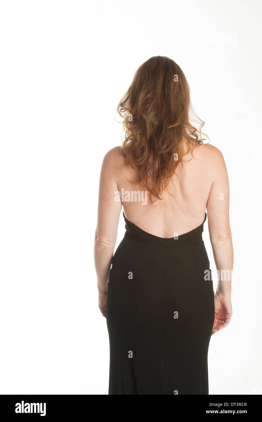 Donna matura in elegante abito nero in piedi contro uno sfondo bianco Foto Stock