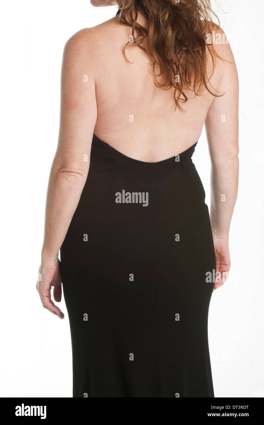 In prossimità di una donna matura dal retro indossando un abito nero in piedi contro uno sfondo bianco Foto Stock