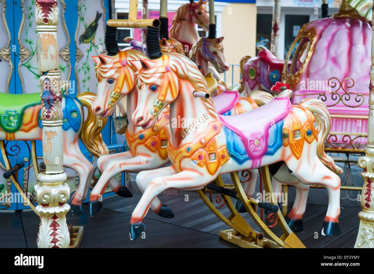 Dipinto luminosamente cavalli in legno su un tradizionale vecchio fiera carosello ride Foto Stock