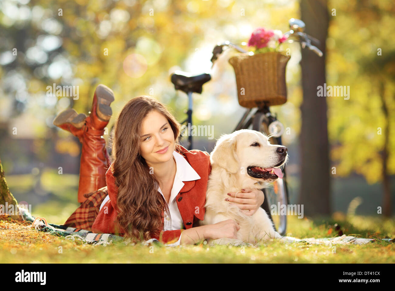 Bellissima femmina sdraiati su un prato verde con un labrador retriever cane in un parco Foto Stock
