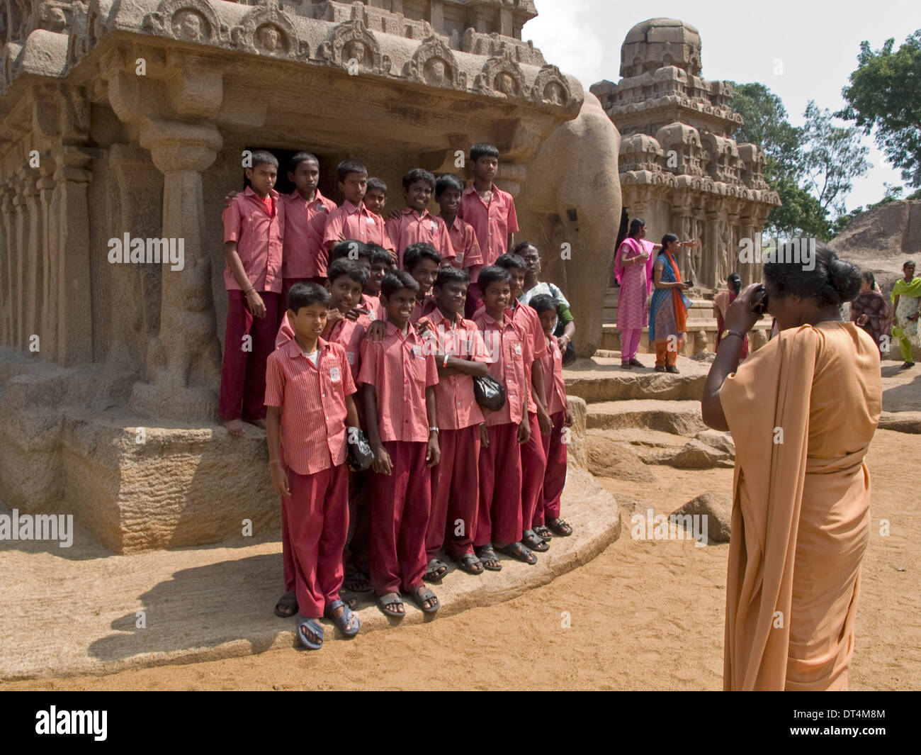 Una classe della scuola indiana i bambini rappresentano per il loro insegnante di foto di gruppo nella parte anteriore di una delle rock-cut templi di Mahabalipuram. Foto Stock