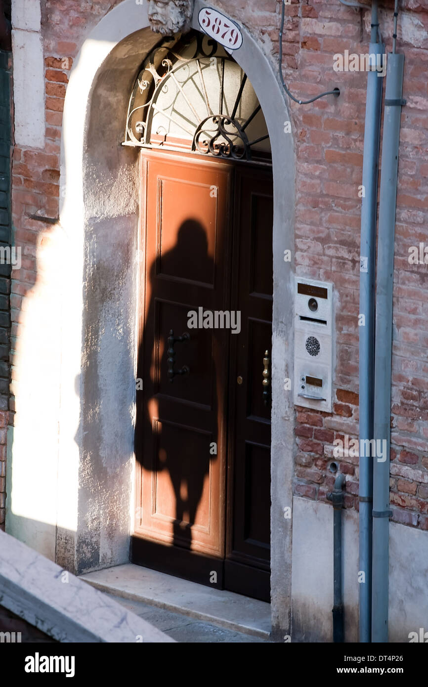 Ombra nera di silhouette di donna all'interno della porta di strada nella parete closeup Foto Stock