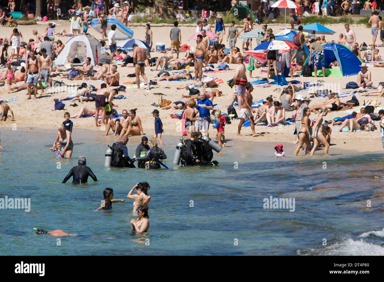 Affollata Shelly Beach a Manly Sydney con gente che si rilassa e prende il sole sulla spiaggia mentre i subacquei si dirigono verso la riserva acquatica di Cabbage Tree Bay Foto Stock