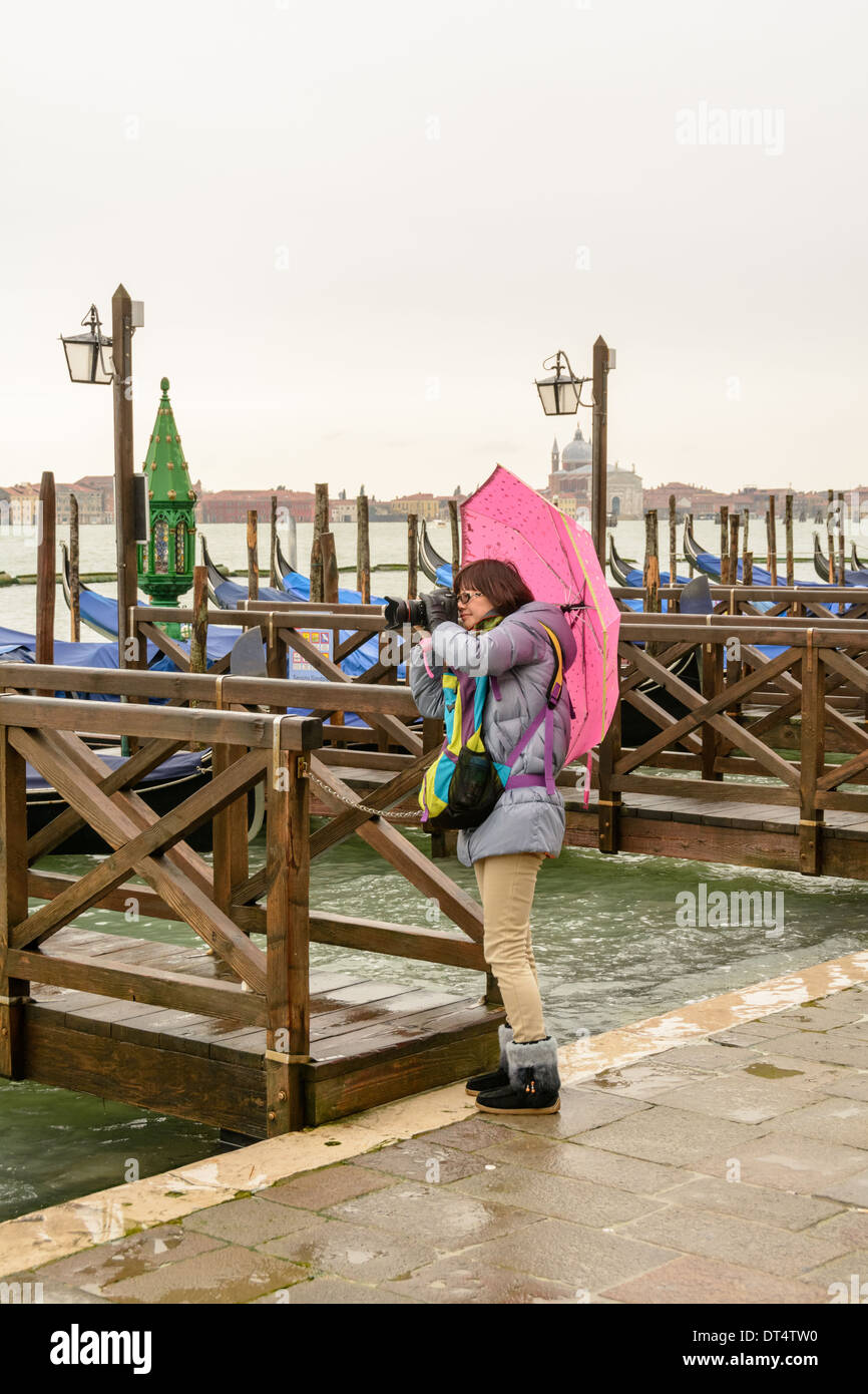 Venezia, Italia. Donna asiatica con ombrello rosa in piedi sulla Mole,  gondola pier di fronte a Piazza San Marco scatta foto con la fotocamera reflex  digitale Canon Foto stock - Alamy