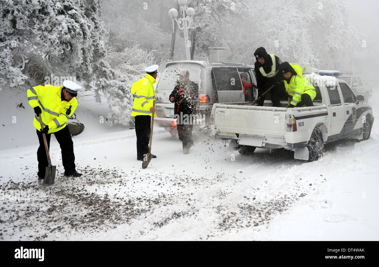 Lushan, cinese della provincia di Jiangxi. Il 9 febbraio, 2014. Il traffico di diffusione poliziotti anti-slittamento sulla sabbia coperte di neve di strada nella zona panoramica del monte Lushan, Cina orientale della provincia di Jiangxi, Febbraio 9, 2014. Lushan testimoniato neve pesante domenica, che ha causato problemi al traffico stradale. © Zhou Ke/Xinhua/Alamy Live News Foto Stock