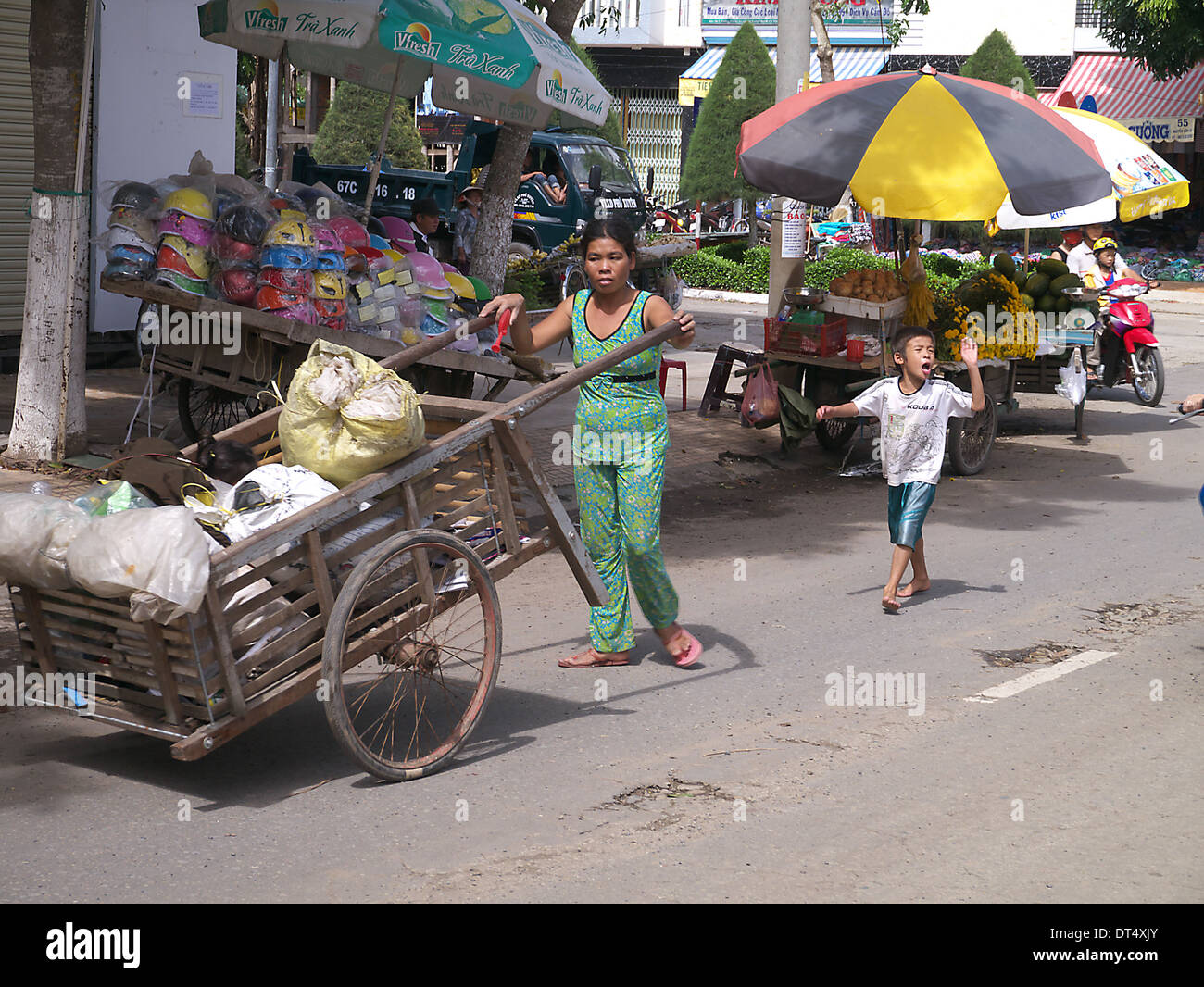 Venditore ambulante con bambino camminando per strada di Phnom Penh Cambogia Foto Stock