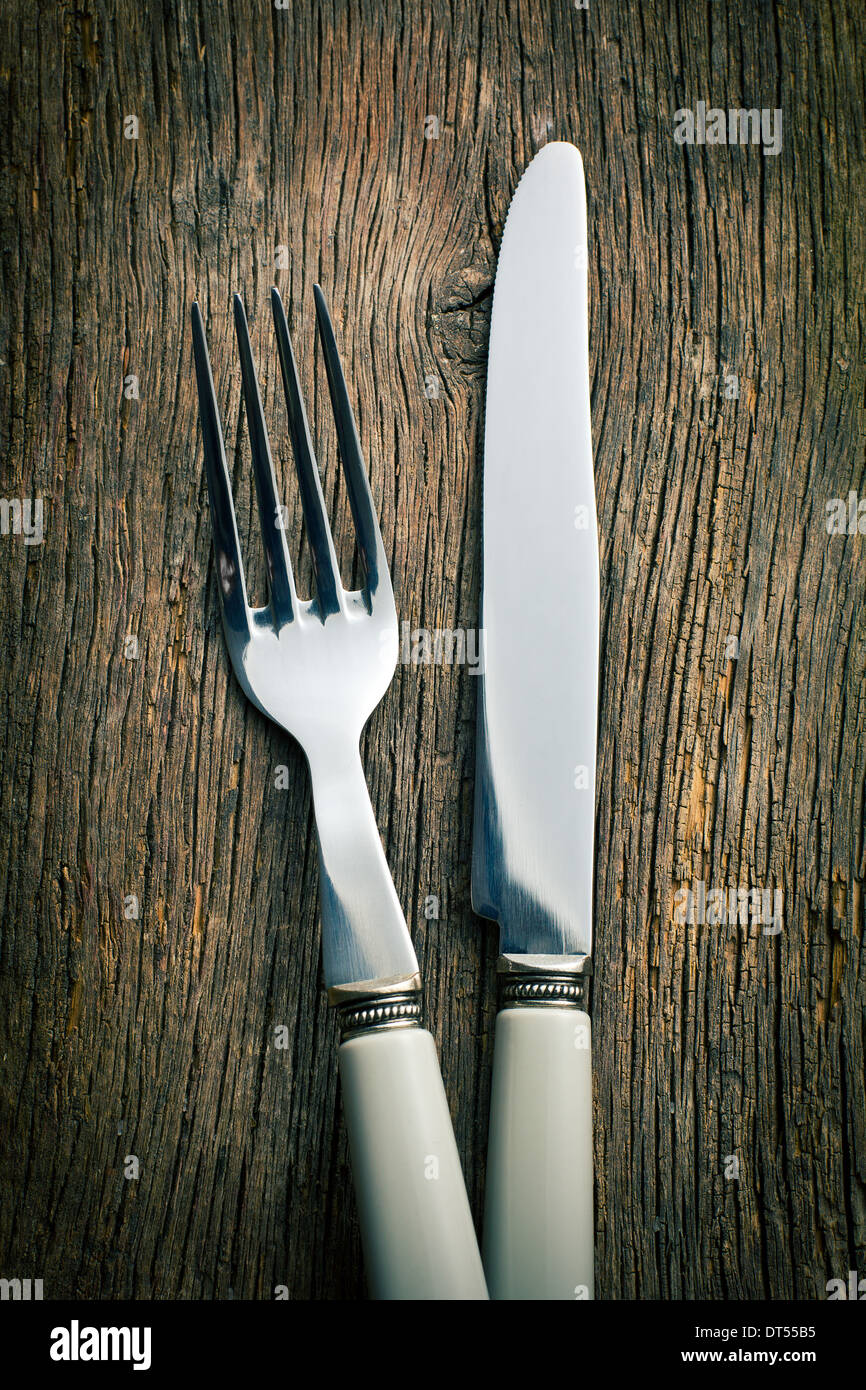 Argento forchetta e coltello sul vecchio sfondo di legno Foto Stock