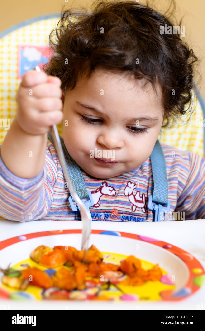 Baby girl di mangiare la zucca sul suo proprio Foto Stock