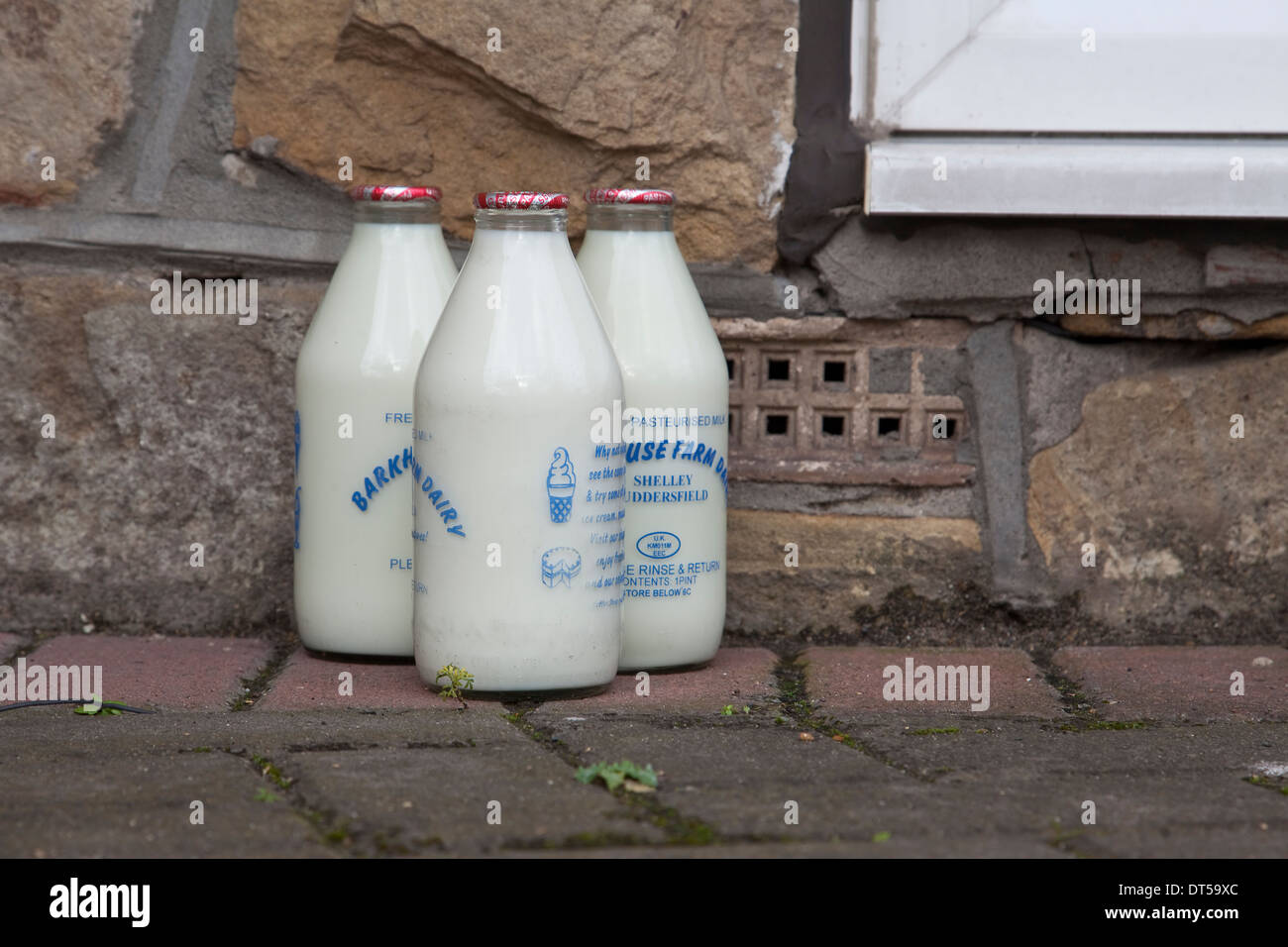 Vetro bottiglie di latte sulla soglia della porta forma tradizionale di consegna da parte di un lattaio in Inghilterra Foto Stock