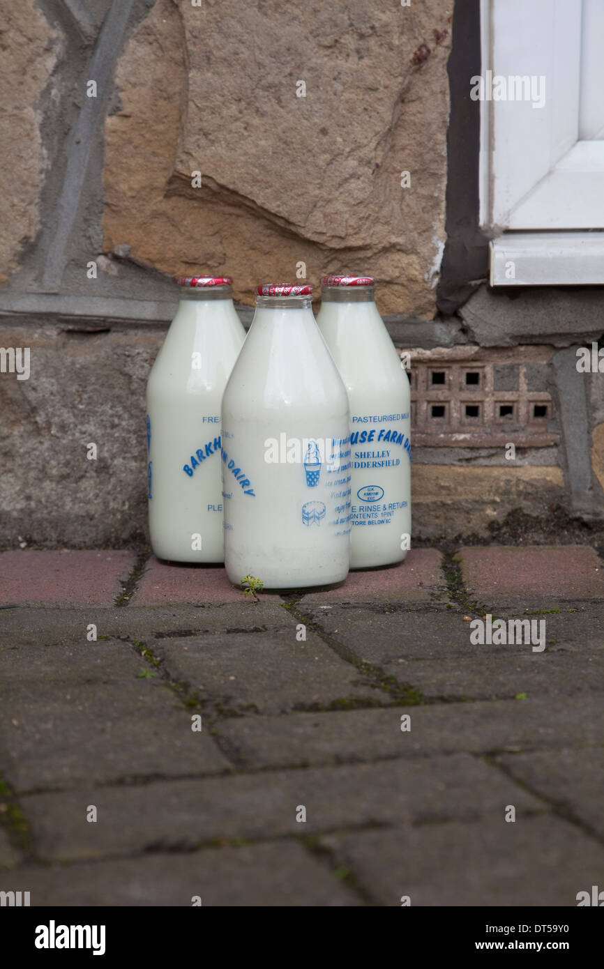 Vetro bottiglie di latte sulla soglia della porta forma tradizionale di consegna da parte di un lattaio in Inghilterra Foto Stock