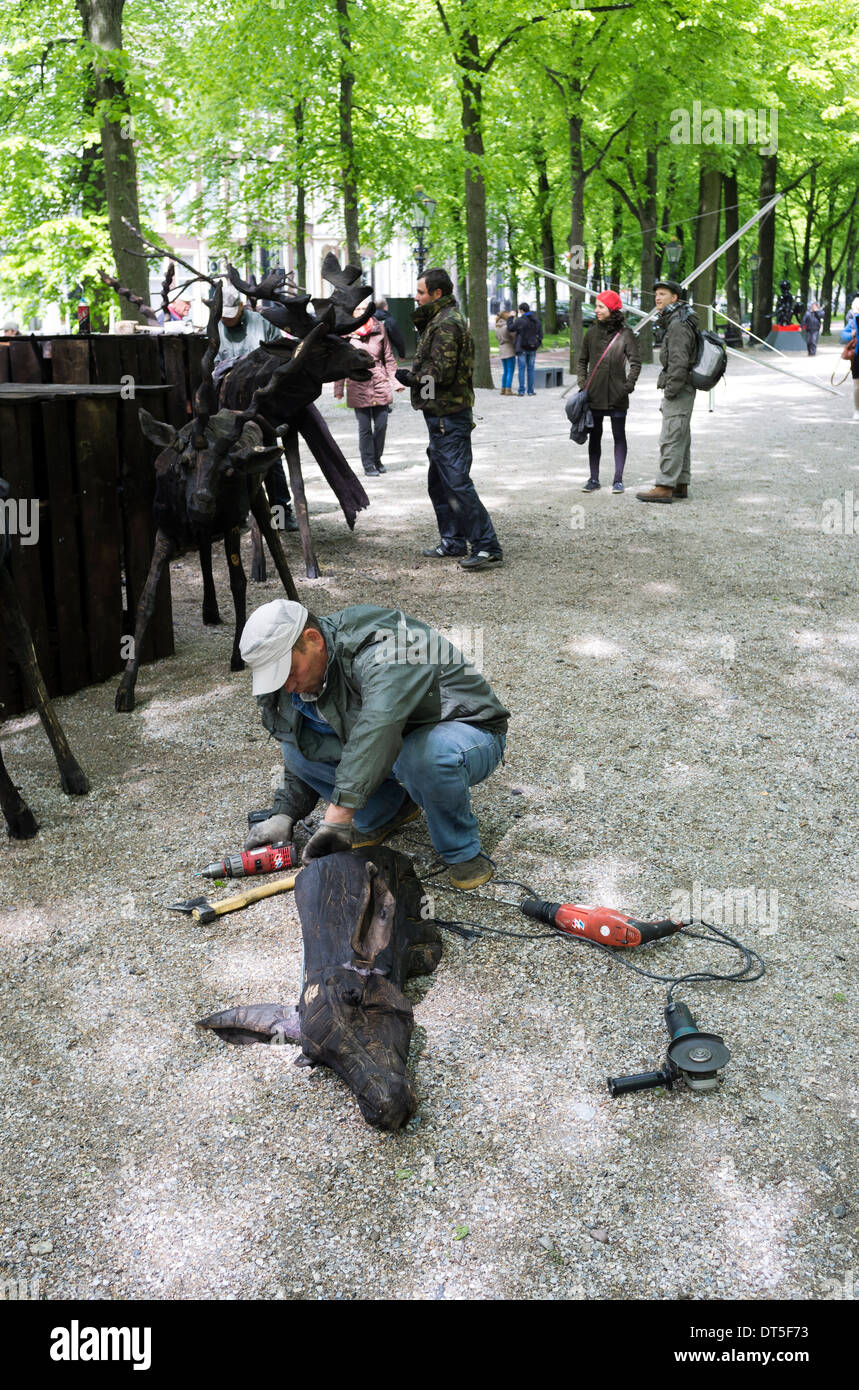 L'uomo intagliare il legno con potenza elettrica strumenti in Lange Voorhout olandese un parco pubblico l'Aia Paesi Bassi Foto Stock