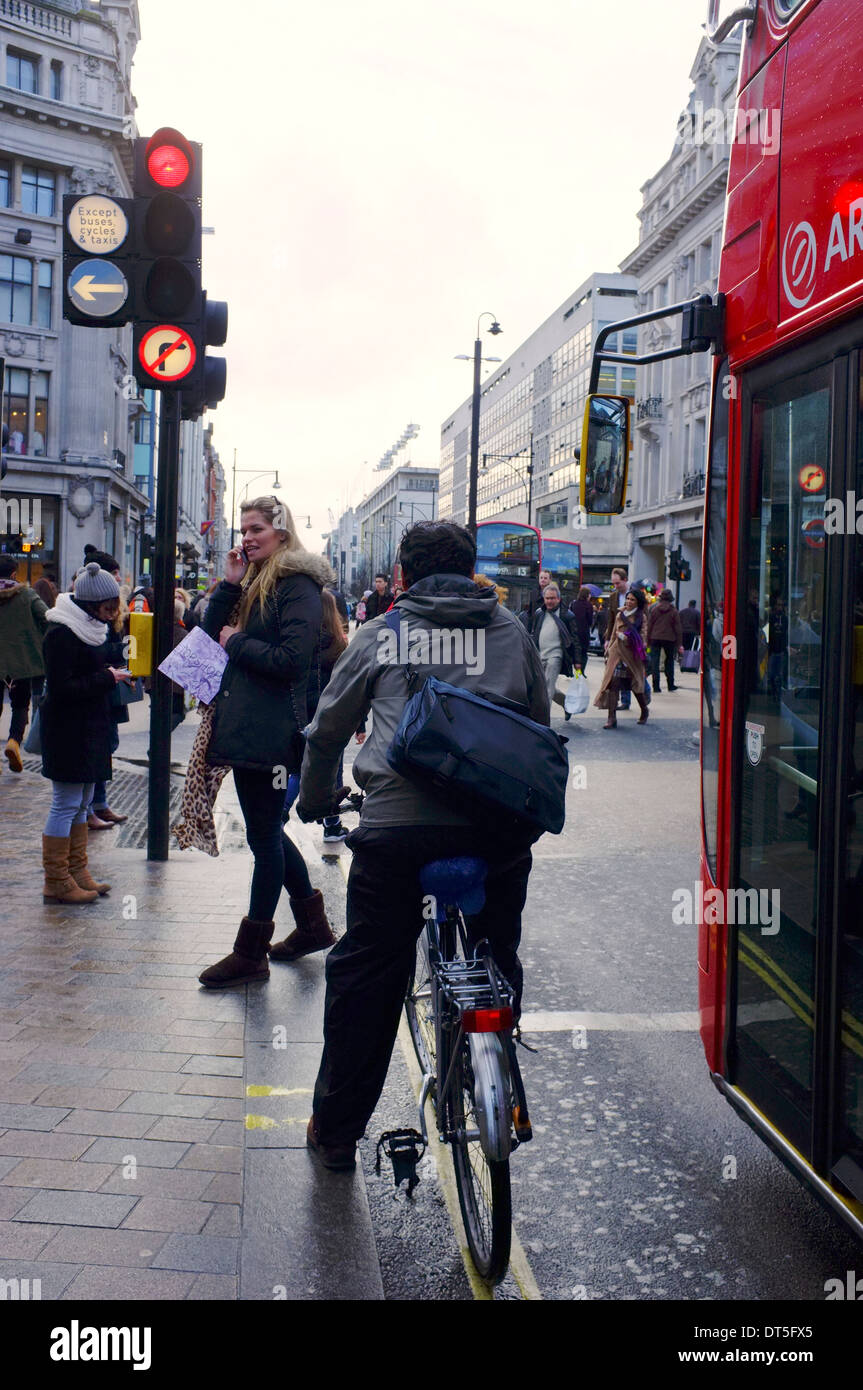 Ciclista con Red London bus al semaforo su Oxford Street, Londra Foto Stock