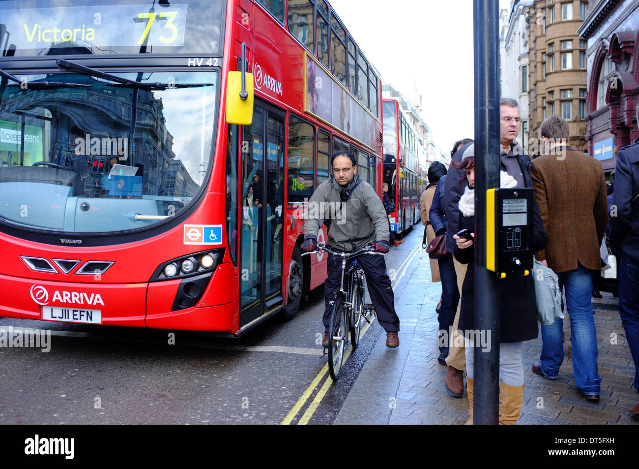 Ciclista con autobus rossi di Londra al semaforo su Oxford Street, Londra Foto Stock