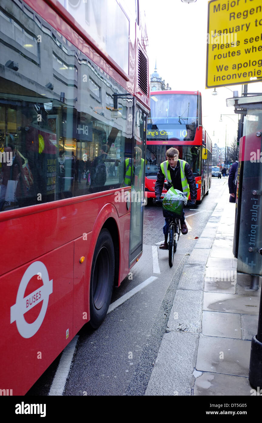 Escursioni in bicicletta tra red double decker bus di Londra Foto Stock