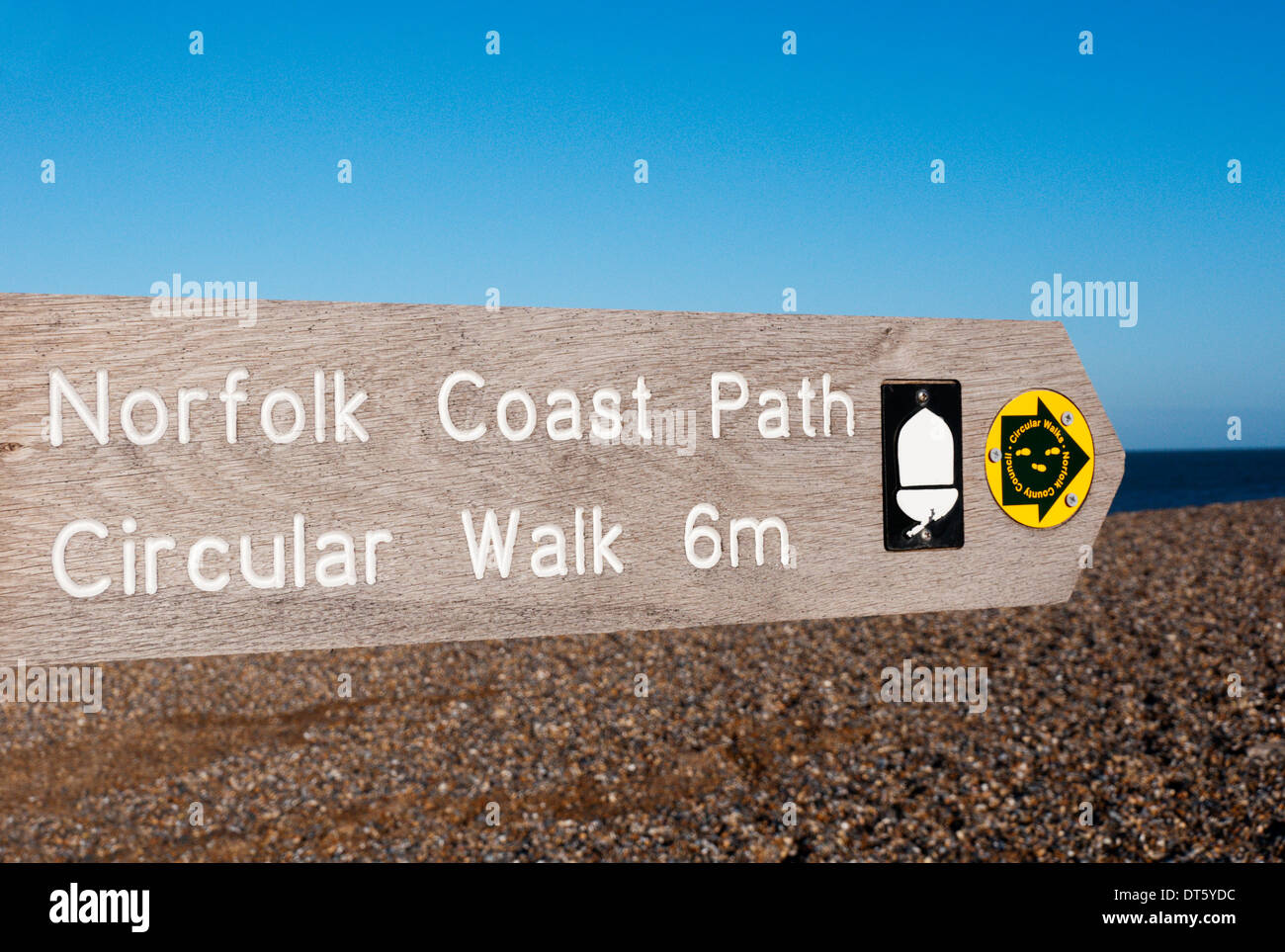 Un cartello per la Norfolk Coast Path rivolta verso destra o verso est lungo la spiaggia di ciottoli a Salthouse in North Norfolk. Foto Stock