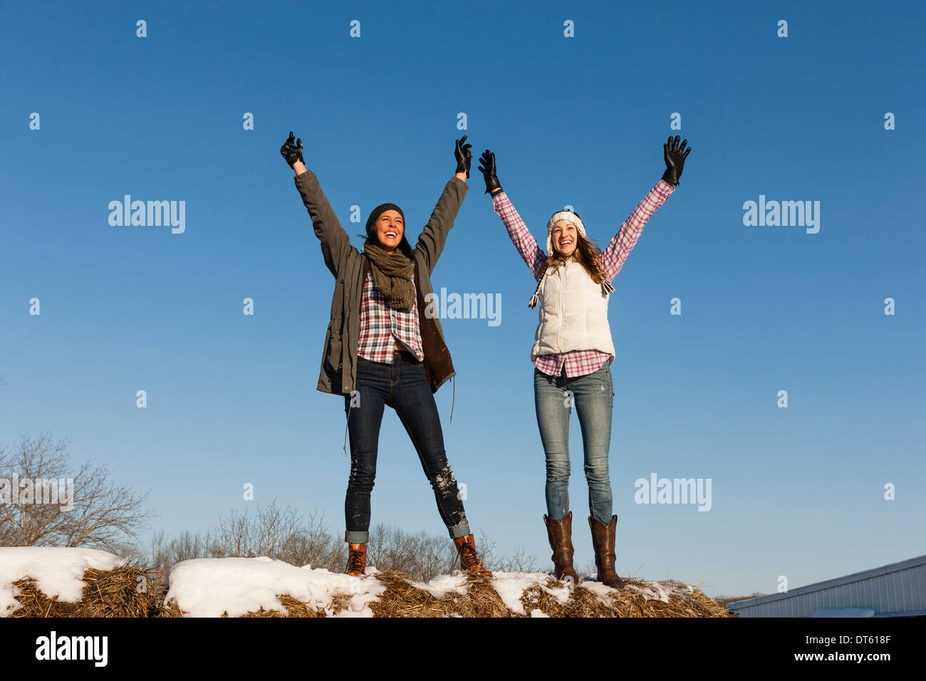Due giovani donne con le braccia sollevate sulla collina di inverno Foto Stock