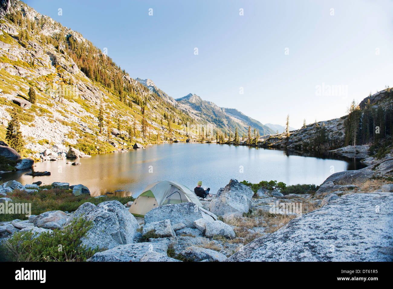 Giovane uomo campeggio al lago remoto, Trinità Alpi, CALIFORNIA, STATI UNITI D'AMERICA Foto Stock