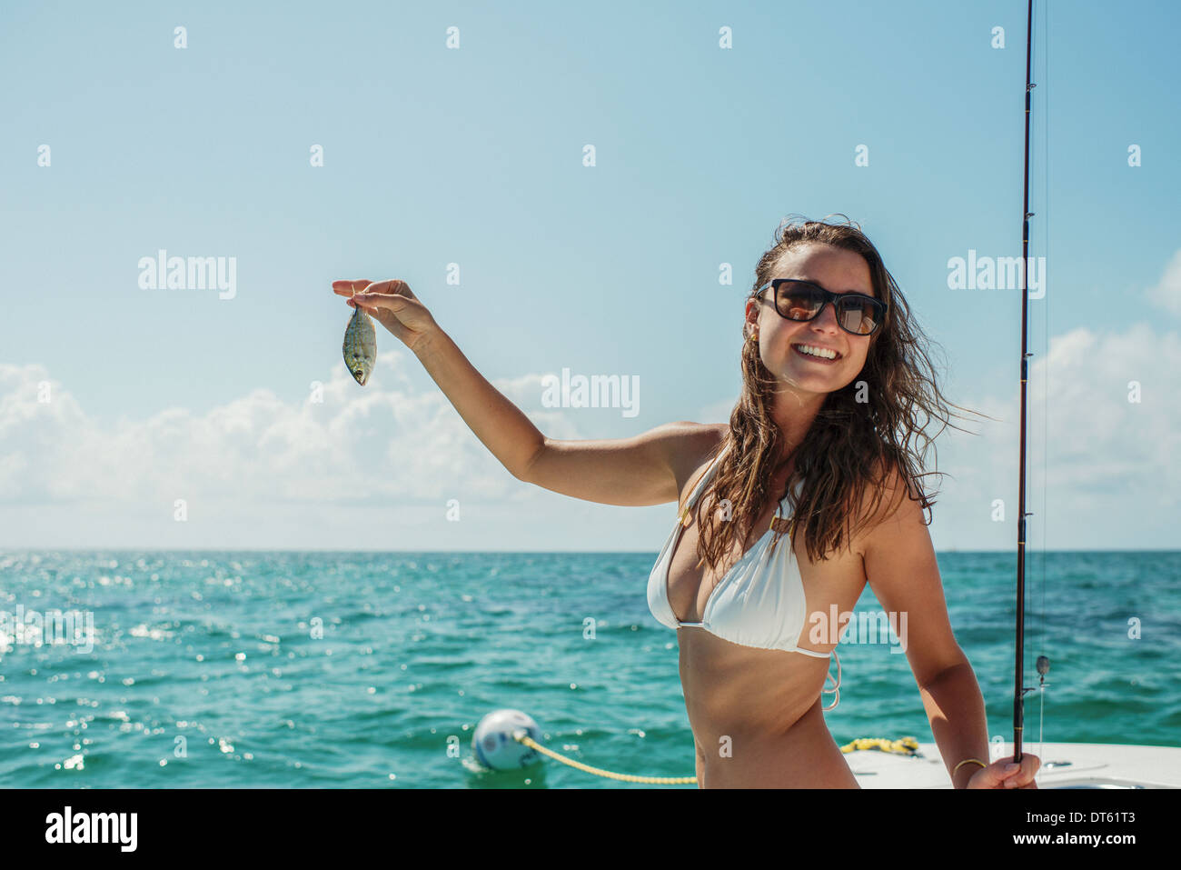 Giovane donna sulla barca tenendo il pesce, Islamorada, Florida Keys, STATI UNITI D'AMERICA Foto Stock