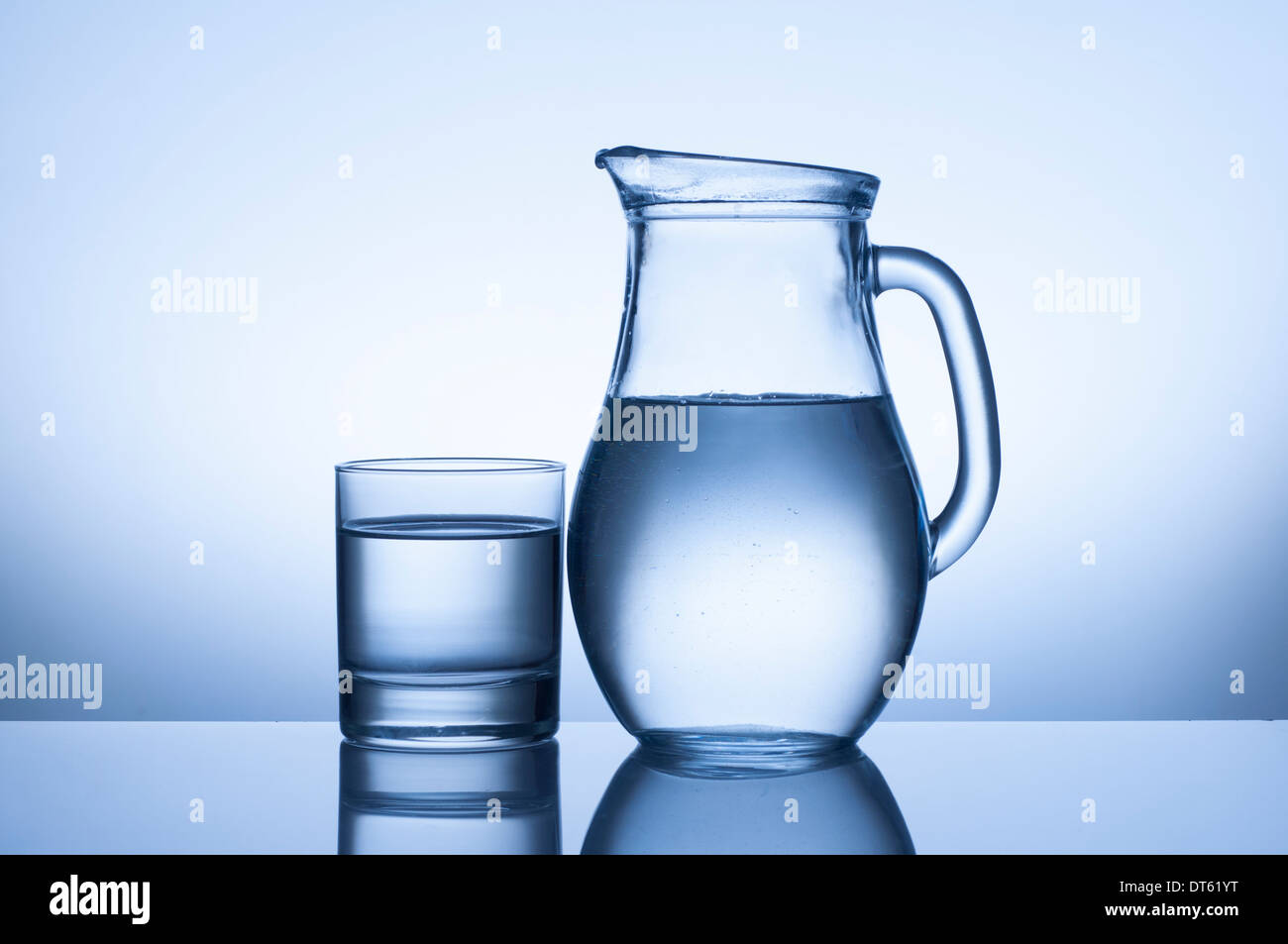 Bicchiere di acqua e la brocca su sfondo blu Foto Stock