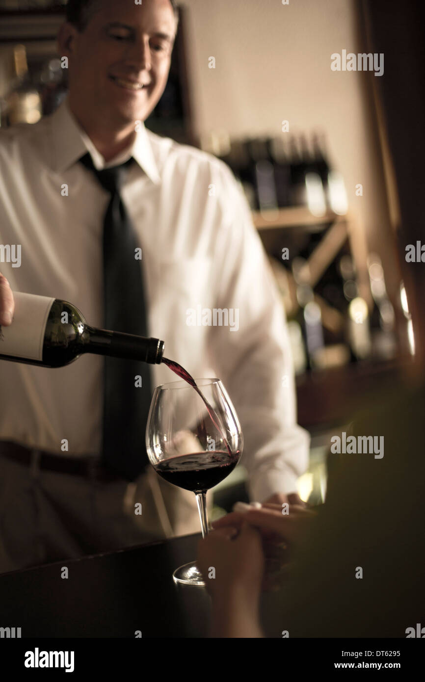 Barista versando il vino rosso in bar Foto Stock