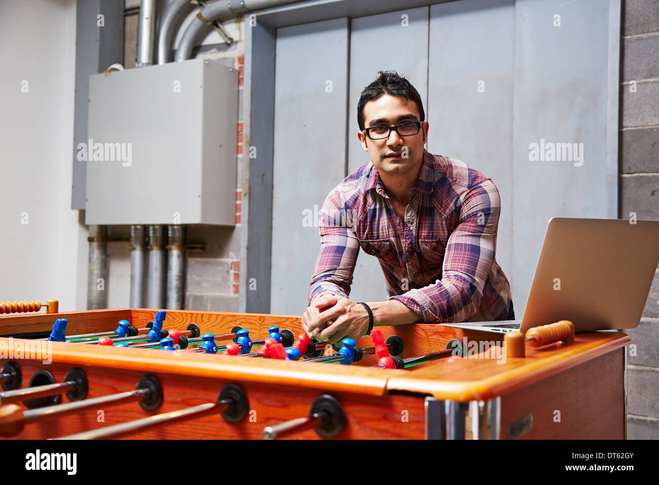 Ritratto di giovane uomo appoggiato su un tavolo da calcio balilla Foto Stock