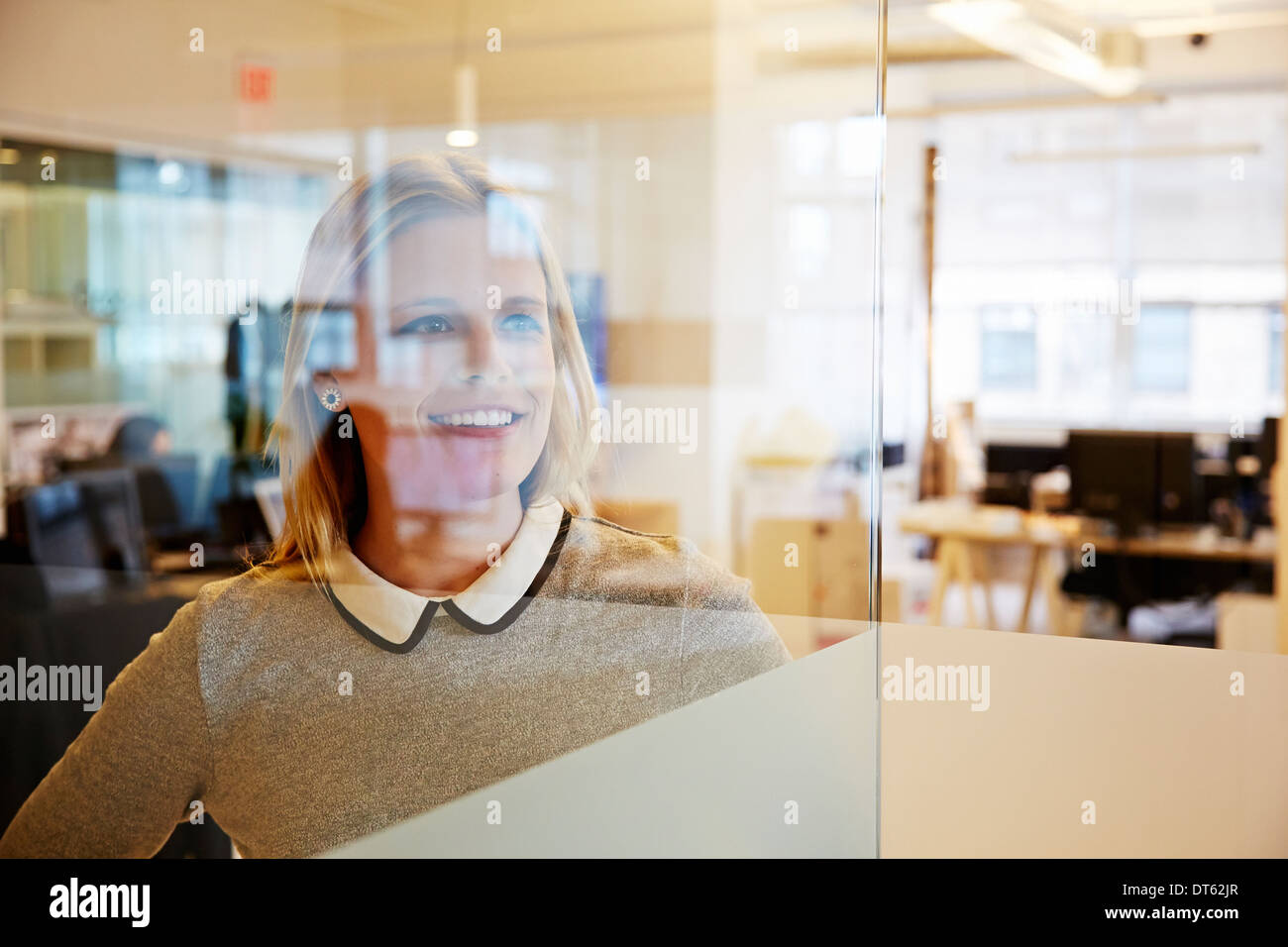 Vista attraverso il vetro della femmina di lavoratore di ufficio Foto Stock