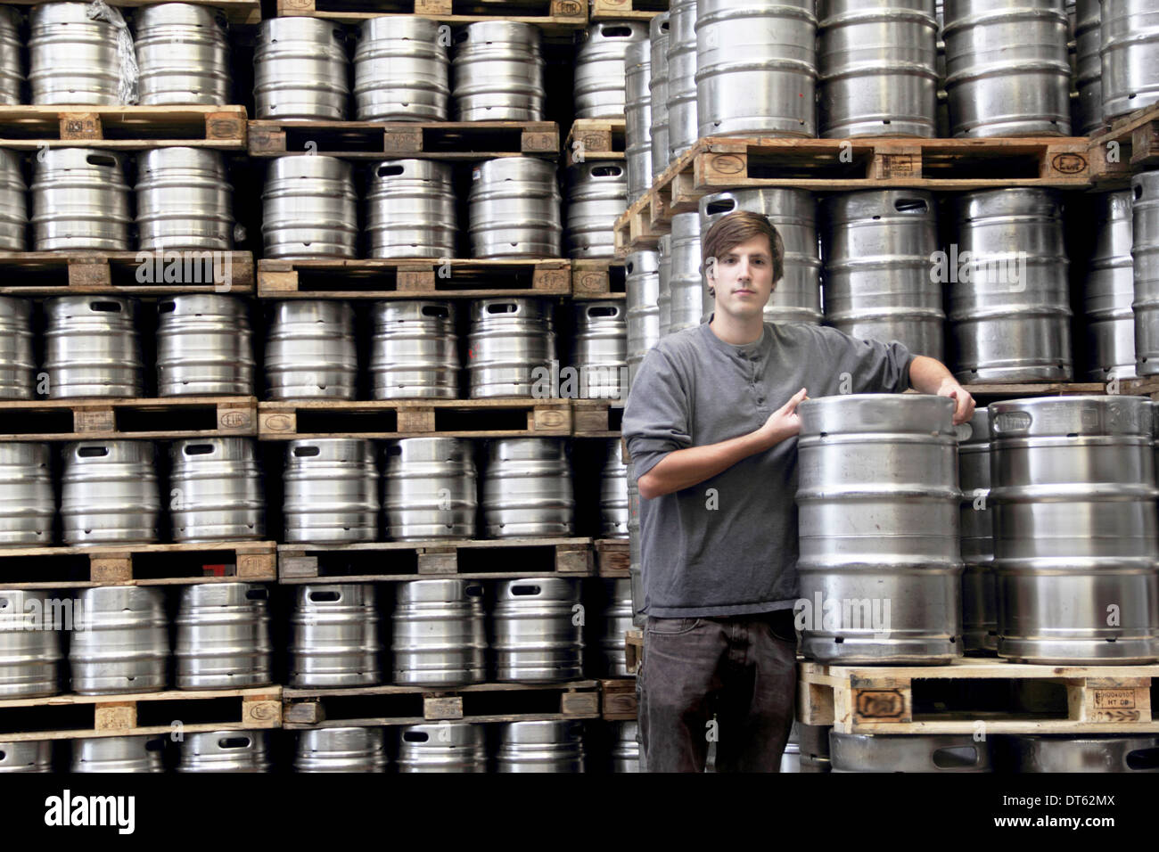 Uomo appoggiato sul barile in fabbrica di birra Foto Stock