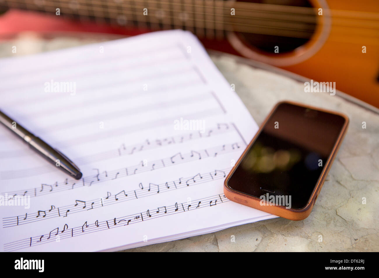 Immagine ritagliata della chitarra, smartphone e foglio di musica Foto Stock