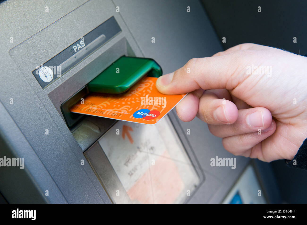 Una donna sta mettendo la sua banca carta in un bancomat per prelevare denaro contante Foto Stock