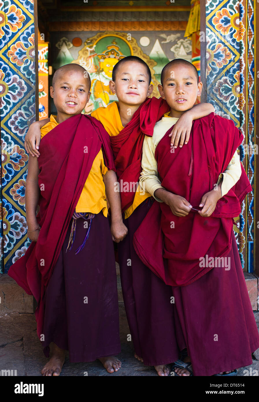 Il Bhutan, Asia del Sud, Punakha, tre giovane debuttante boy monaci in piedi nella porta di Chimi Lakhang tempio della vecchia capitale. Foto Stock