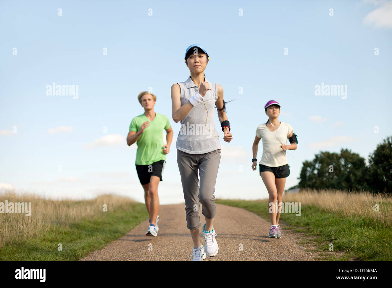Tre giovani adulti jogging lungo la via del campo Foto Stock