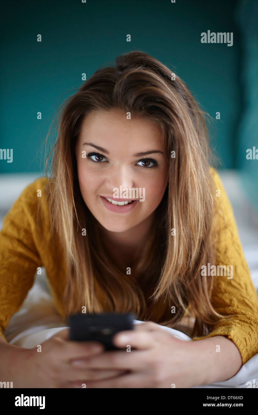 Ritratto di ragazza adolescente in camera da letto con lo smartphone Foto Stock