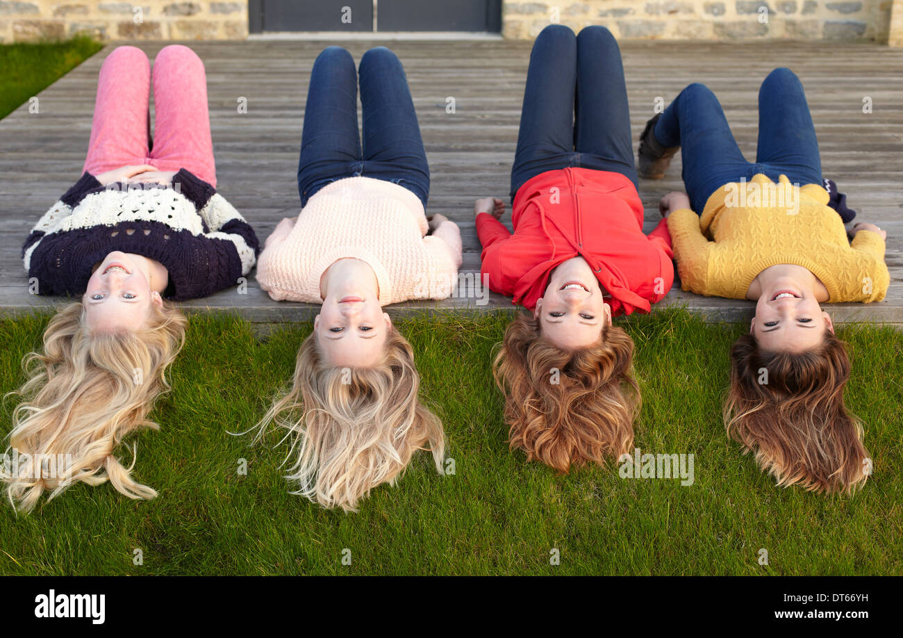 Quattro ragazze adolescenti giacente sul patio e guardando indietro Foto Stock