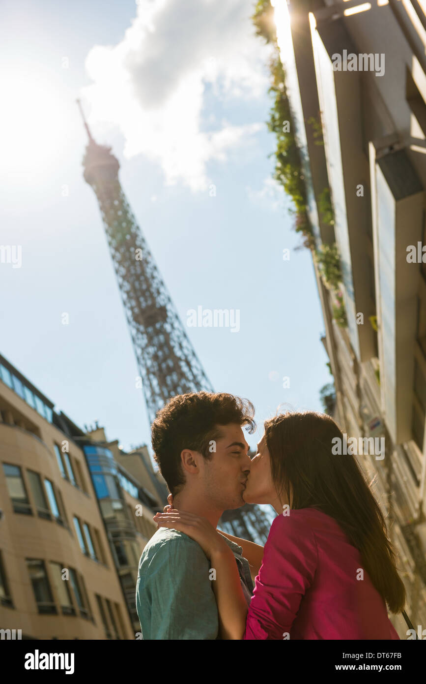 Coppia giovane la condivisione di un bacio di fronte alla Torre Eiffel, Parigi, Francia Foto Stock