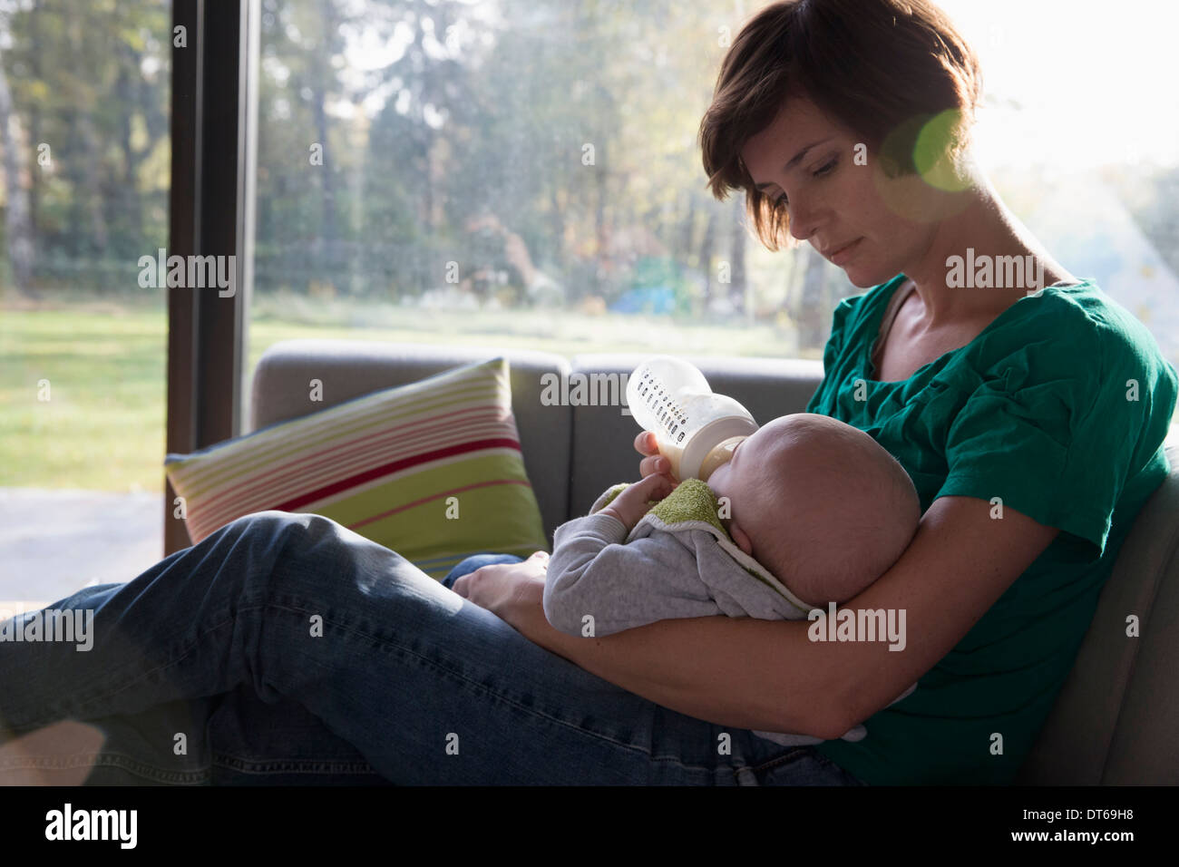 Madre biberon per bambino sul divano Foto Stock