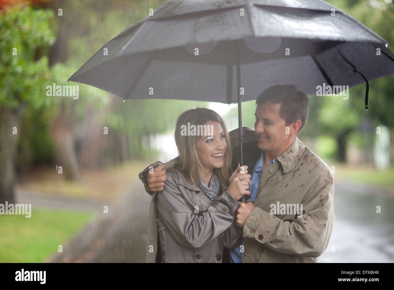 Giovane donna e uomo maturo passeggiate nel parco delle piogge Foto Stock