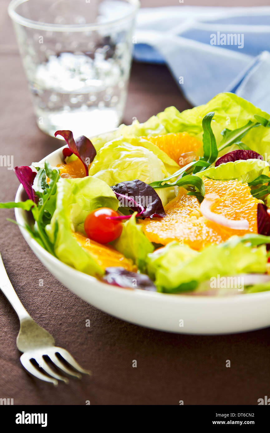 Arancione con rucola e melograno insalata in una ciotola Foto Stock