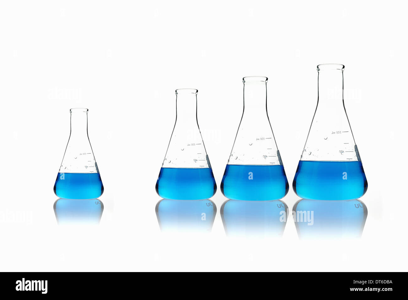 Bicchiere conico palloni scientifici di contenimento liquidi blu. Allineate in ordine di dimensione, con un set apart. Foto Stock