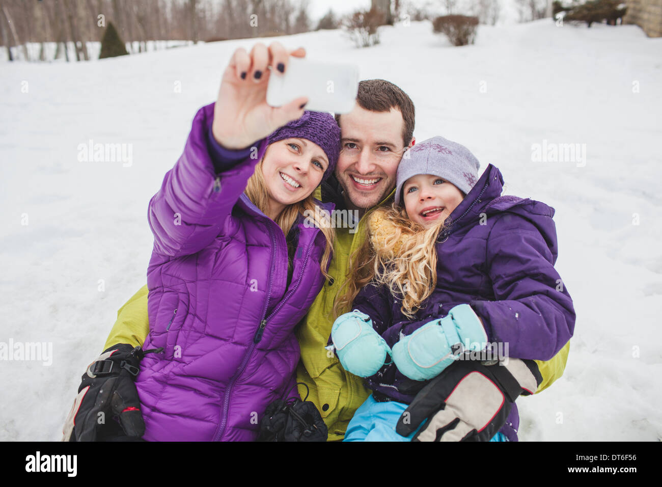 Il padre e la madre con la figlia tenendo ritratto di famiglia con il telefono cellulare Foto Stock