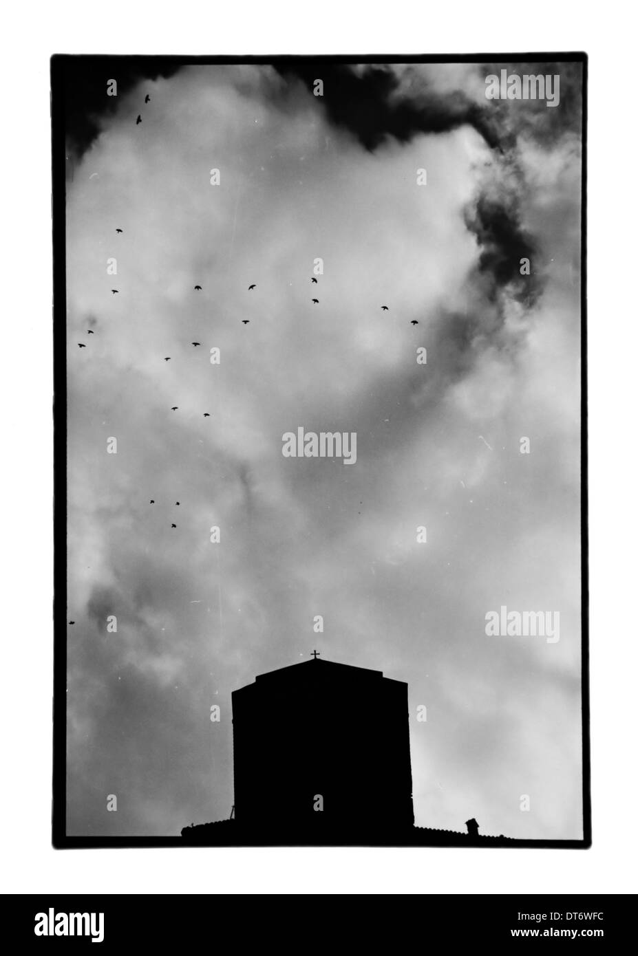 Chiesa sotto il cielo nuvoloso e stormo di uccelli in volo. Bianco e nero stampa camera oscura con polvere e graffi. Meteora, Grecia. Foto Stock